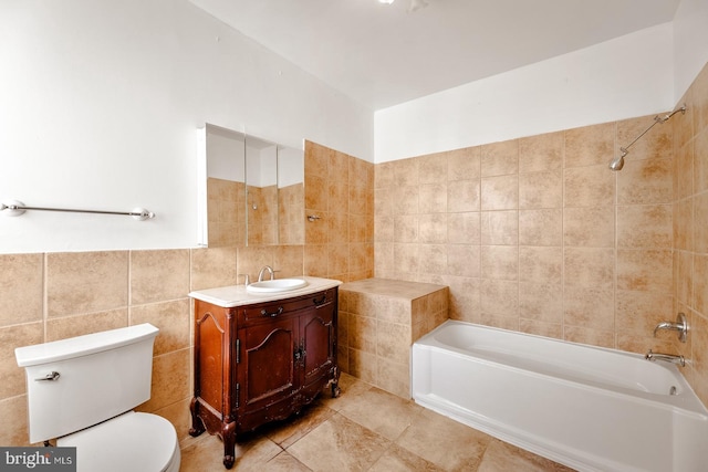 full bathroom with tile walls, tile patterned floors, vanity, tiled shower / bath combo, and toilet