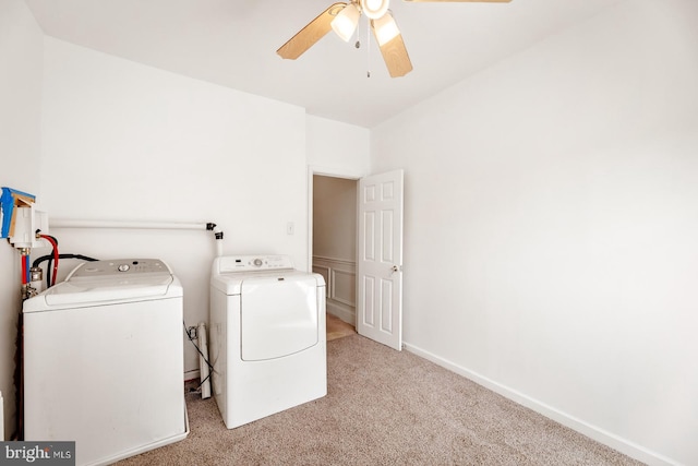 clothes washing area featuring ceiling fan, washer and dryer, and light carpet