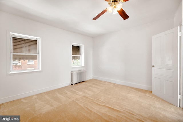 carpeted spare room featuring ceiling fan and radiator