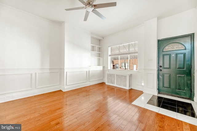 entryway with ornamental molding, hardwood / wood-style flooring, and ceiling fan