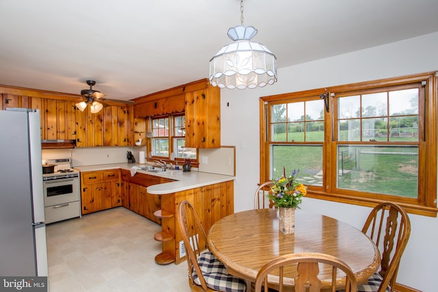 kitchen featuring stainless steel refrigerator, ceiling fan, white gas range oven, and sink