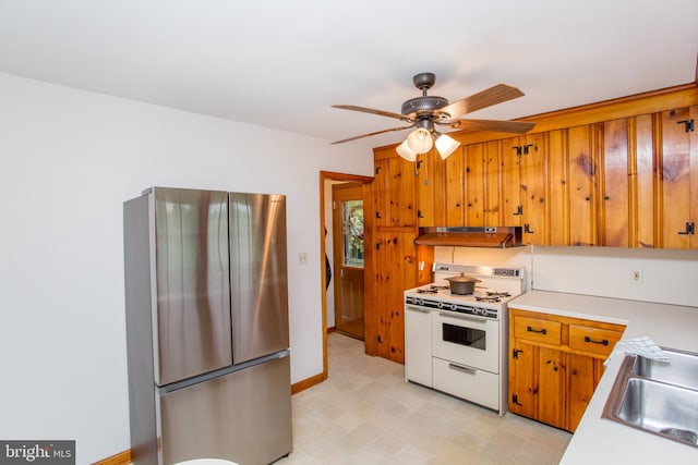 kitchen with ventilation hood, white gas stove, sink, stainless steel fridge, and ceiling fan