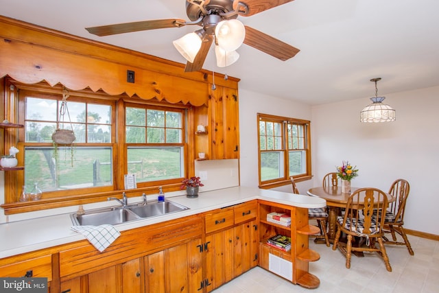 kitchen with a wealth of natural light, pendant lighting, ceiling fan, and sink