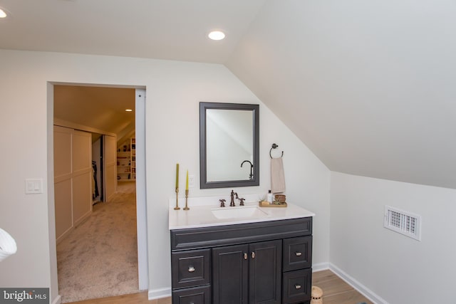 bathroom with hardwood / wood-style floors, vanity, and vaulted ceiling