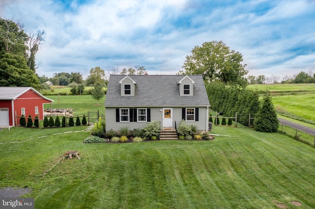 cape cod home with an outbuilding, a rural view, and a front yard