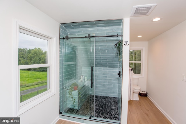 bathroom featuring a healthy amount of sunlight, toilet, hardwood / wood-style floors, and an enclosed shower