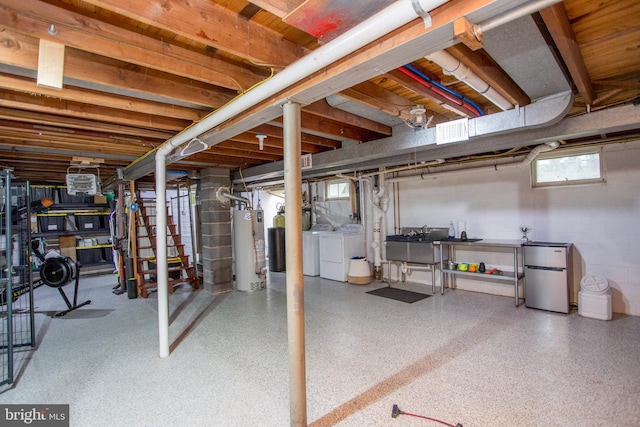 basement featuring stainless steel refrigerator, sink, independent washer and dryer, and water heater