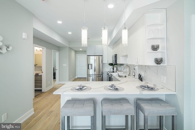 kitchen featuring appliances with stainless steel finishes, a breakfast bar area, white cabinetry, and kitchen peninsula