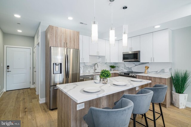 kitchen featuring stainless steel appliances, white cabinetry, a center island, and light hardwood / wood-style flooring