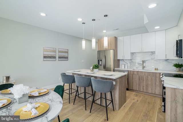 kitchen with stainless steel appliances, pendant lighting, a center island, sink, and white cabinetry