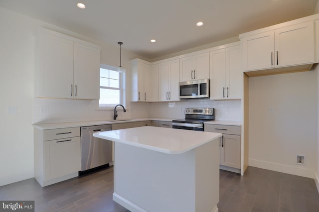 kitchen with a kitchen island, dark hardwood / wood-style flooring, sink, decorative light fixtures, and stainless steel appliances