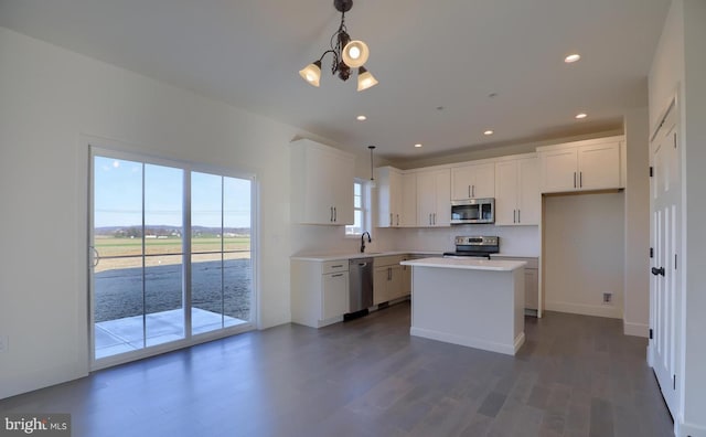 kitchen with dark hardwood / wood-style floors, pendant lighting, a kitchen island, white cabinetry, and appliances with stainless steel finishes