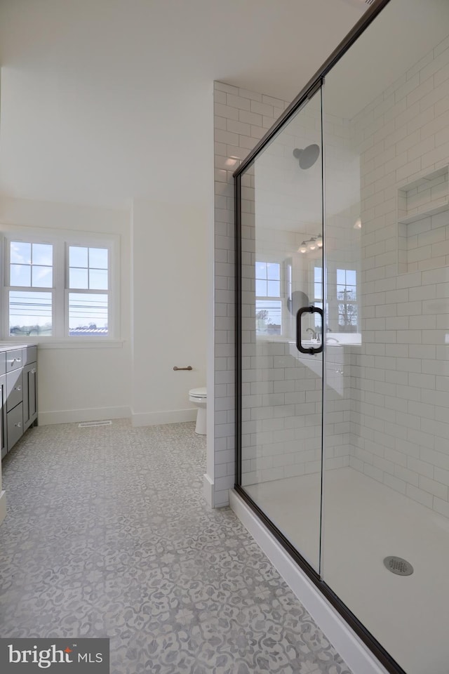 bathroom featuring tile patterned flooring, vanity, walk in shower, and toilet