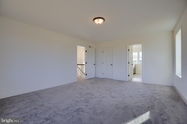 unfurnished bedroom with light colored carpet and ensuite bathroom