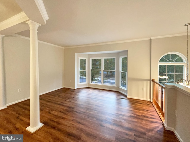 empty room with plenty of natural light, dark wood-type flooring, ornamental molding, and decorative columns