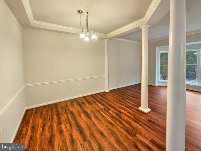 spare room featuring an inviting chandelier, decorative columns, hardwood / wood-style floors, and ornamental molding