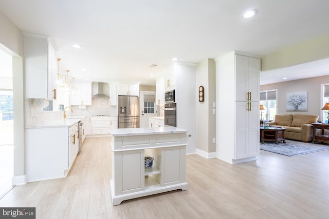 kitchen featuring light wood-type flooring, tasteful backsplash, black appliances, wall chimney range hood, and white cabinets