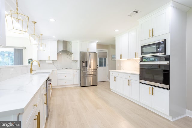 kitchen featuring wall chimney exhaust hood, light wood-type flooring, black appliances, and backsplash