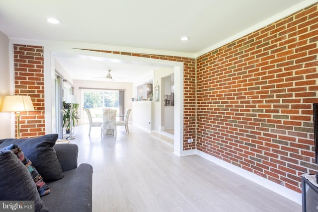 living room featuring crown molding, recessed lighting, brick wall, light wood-type flooring, and baseboards