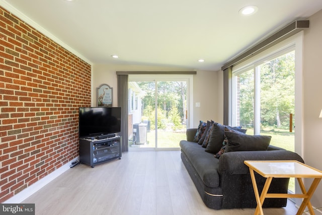 living area with an accent wall, light wood-type flooring, brick wall, and recessed lighting