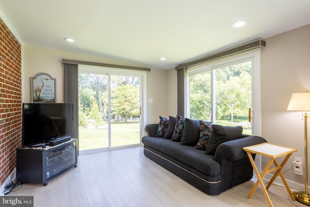 living room featuring light wood finished floors, plenty of natural light, brick wall, and recessed lighting