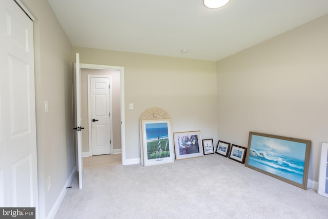 interior space featuring light colored carpet and baseboards