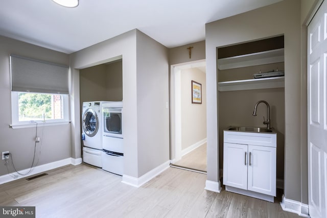 laundry area with visible vents, light wood-style floors, a sink, independent washer and dryer, and baseboards