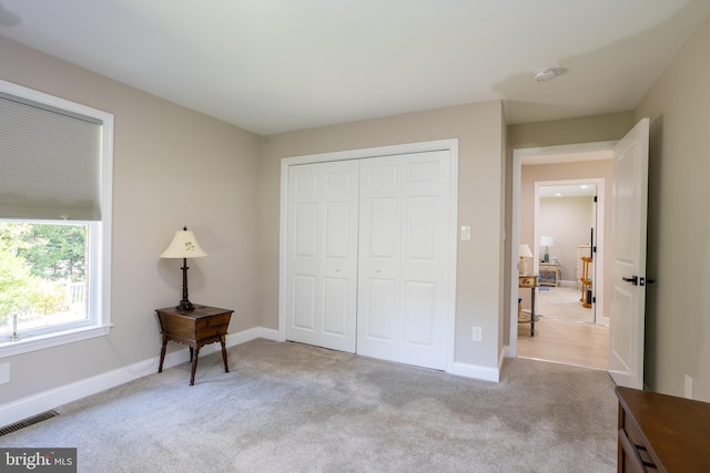 bedroom featuring light carpet, a closet, visible vents, and baseboards