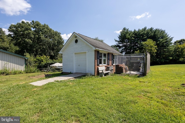 exterior space featuring a garage, a yard, and an outbuilding