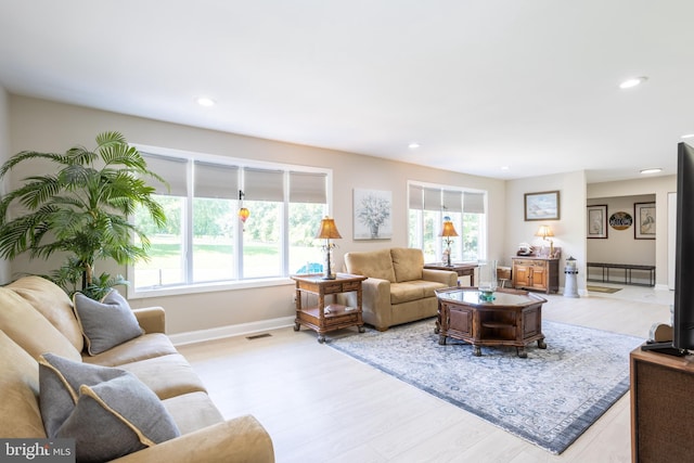 living area with visible vents, light wood-style flooring, and a wealth of natural light