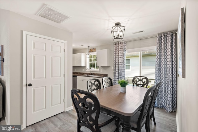 dining space featuring a chandelier, sink, and light hardwood / wood-style flooring