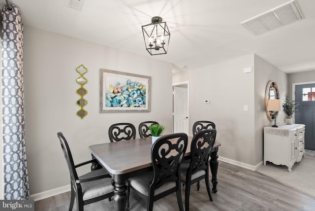 dining space featuring hardwood / wood-style flooring and a notable chandelier