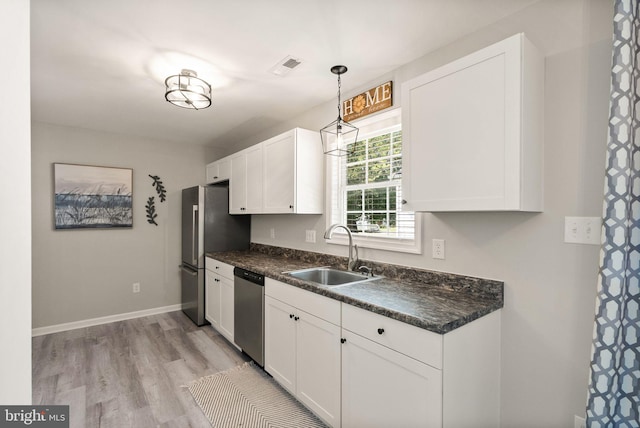 kitchen with light hardwood / wood-style flooring, sink, hanging light fixtures, appliances with stainless steel finishes, and white cabinets