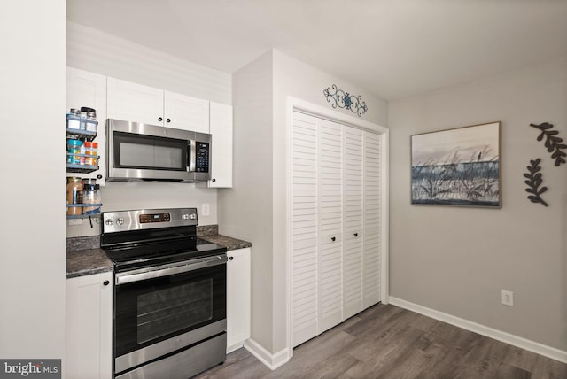 kitchen with appliances with stainless steel finishes, dark hardwood / wood-style flooring, and white cabinets