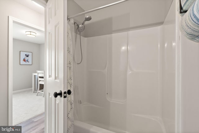 bathroom featuring wood-type flooring and shower / bath combo with shower curtain