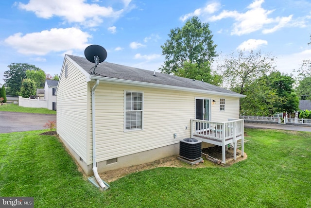 rear view of house featuring a lawn and central AC unit