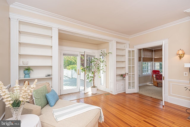 living area with french doors, light hardwood / wood-style floors, crown molding, and a healthy amount of sunlight