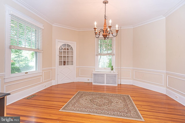 unfurnished dining area with a healthy amount of sunlight, hardwood / wood-style floors, and a notable chandelier