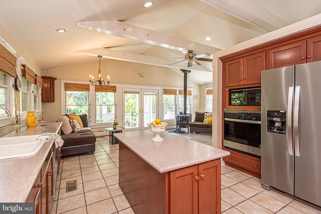 kitchen featuring vaulted ceiling, ceiling fan with notable chandelier, stainless steel appliances, sink, and light tile patterned flooring