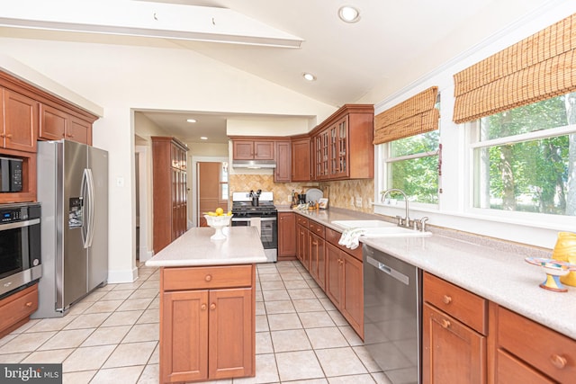 kitchen featuring light tile patterned floors, vaulted ceiling, appliances with stainless steel finishes, sink, and decorative backsplash