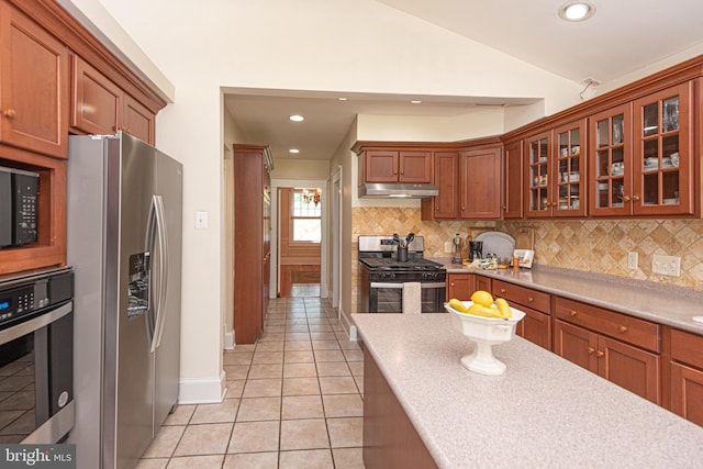 kitchen with lofted ceiling, backsplash, light tile patterned floors, and appliances with stainless steel finishes