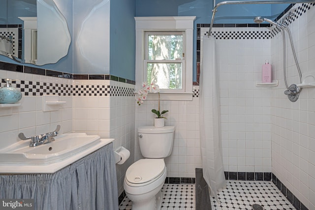 bathroom featuring a shower with shower curtain, vanity, tile walls, toilet, and tile patterned floors