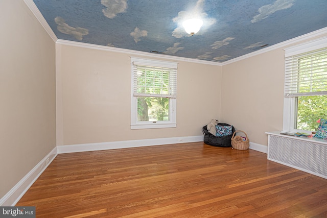 empty room with ornamental molding, radiator, and hardwood / wood-style flooring