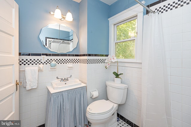 bathroom with toilet, walk in shower, tile patterned floors, vanity, and tile walls