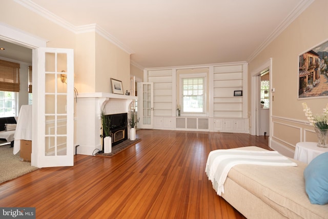 living room with crown molding, built in features, and hardwood / wood-style floors