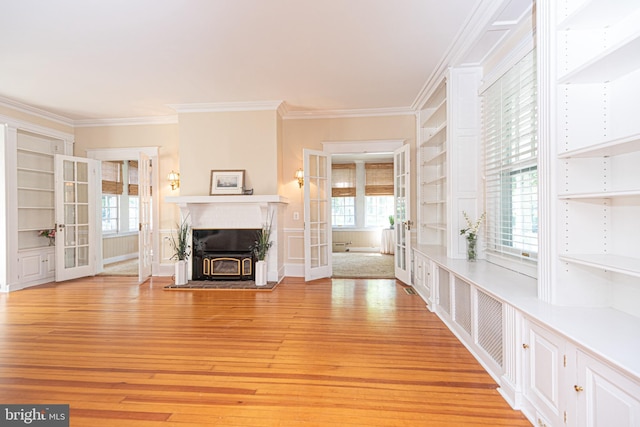 unfurnished living room featuring a fireplace, french doors, light hardwood / wood-style flooring, and a healthy amount of sunlight