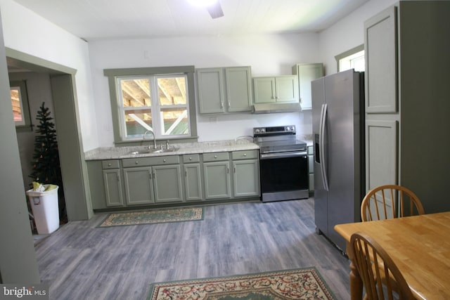 kitchen with dark wood-style floors, ceiling fan, appliances with stainless steel finishes, under cabinet range hood, and a sink