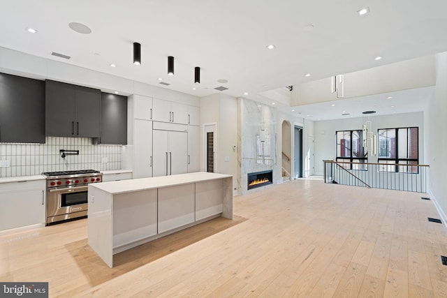 kitchen featuring high end appliances, modern cabinets, light countertops, and decorative backsplash