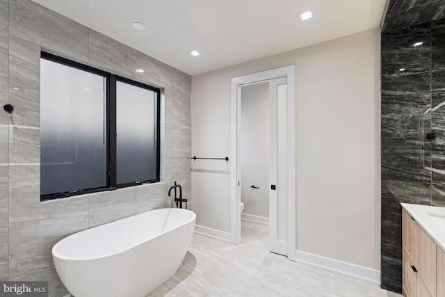 full bathroom with toilet, recessed lighting, vanity, tile walls, and a freestanding bath