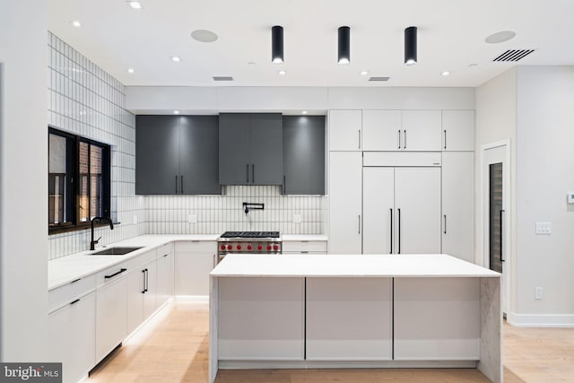 kitchen with light countertops, a sink, white cabinetry, and a center island